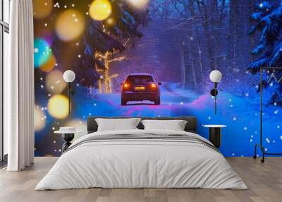 Car driving through a snowy forest with festive lights in winter. Wall mural