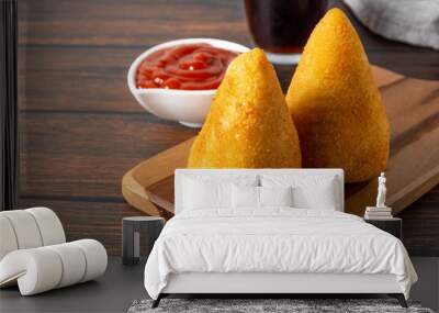 coxinha traditional brazilian snack fried in oil and stuffed with bovine meat or chicken meat, with ketchup and soda on the background over wooden table Wall mural