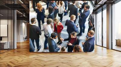 Diverse professionals engage in lively networking at a business conference, exchanging ideas and building connections in a bustling environment. Wall mural