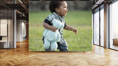 Young toddler walking through a field Wall mural