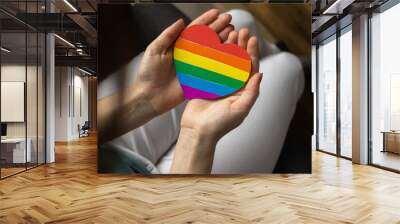 LGBT community background with copy space. Girl hand with heart shaped LGBT rainbow flag and symbol Wall mural