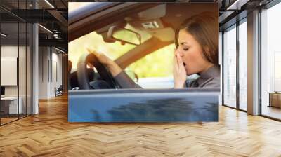 sleepy fatigued yawning young woman driving her car Wall mural