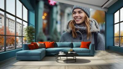 Happy young woman with a smile in a gray vintage coat with a knitted cap with coffee walking outdoors in the city. Made with generative ai Wall mural