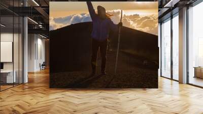 Climber celebrating on the top of the Acatenango volcano in Guatemala with the sunset in the background - silhouette of woman with the peace symbol on top of the mountain Wall mural