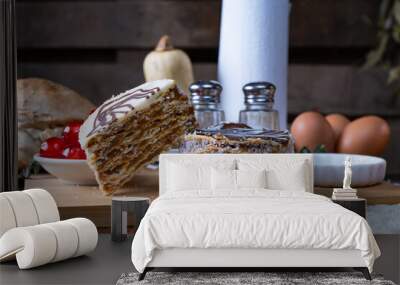 Freshly baked cakes with different toppings on the table with baking ingredients on the background Wall mural