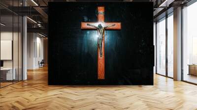 A wooden and bronze crucifix on a dark surface with a light behind Wall mural