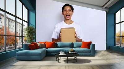 Asian young man happy wearing white shirt gesture holding package box Wall mural