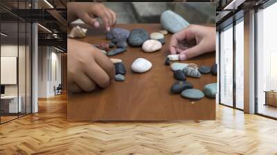 The child is playing with stones from children’s activities.kid draws something for her handcraft picture. Wall mural