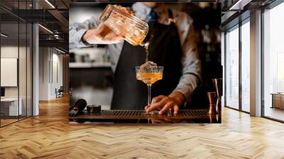 barman gently pours finished cold cocktail from glass shaker into glass. Wall mural