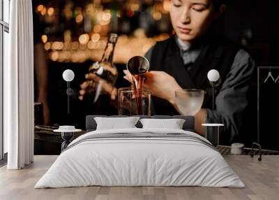 Bartender girl pouring a delicious brown cocktail from the steel jigger Wall mural