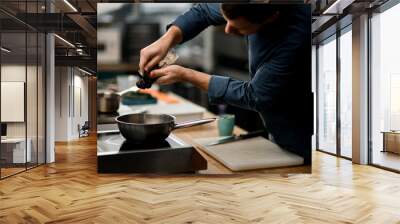 man chef holds package with product and puts it on frying pan Wall mural