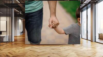 Strong father hand holding a little hand of his son Wall mural