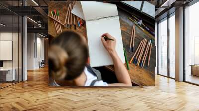 top view on sketchbook on wooden table in which young woman draws Wall mural