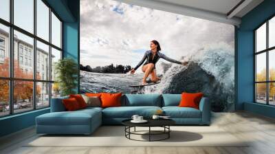 woman having fun sitting on surf board and touching the water with her hand. Wall mural