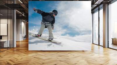 Young female snowboarder running down the mountain slope Wall mural