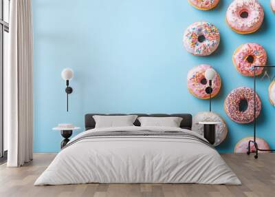 Glazed and decorated donuts for a sweet snack, laid out on a blue background with space for text. Wall mural