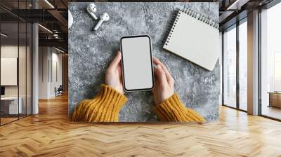 Mockup image of woman's hands holding smartphone with blank screen on gray table background, top view Wall mural