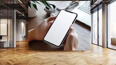 Mockup image of woman's hands holding smartphone with blank screen on gray table background, top view Wall mural