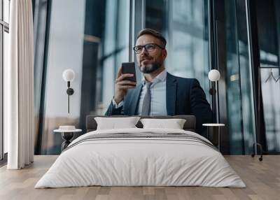 Portrait of businessman talking on mobile phone while standing in office Wall mural