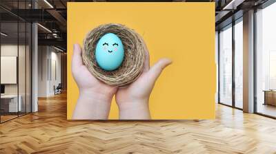 Preparation for the Easter holiday. Egg and Easter decor. Funny face painted on an eggon a bright background Wall mural