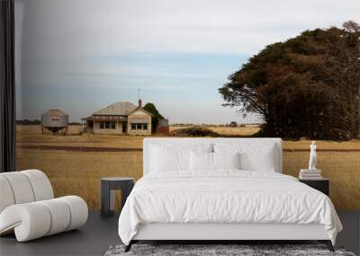 Panoramic image of an old timber worn out abandoned traditional Australian farm house in the middle of a newly harvested field on a agricultural property in rural Victoria, Australia Wall mural