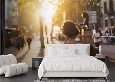 Girl enjoying sunset and chatting with friends via smartphone on the city streets Wall mural