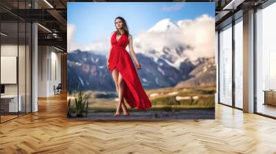 girl in a long red dress on a background of majestic mountains. Wall mural