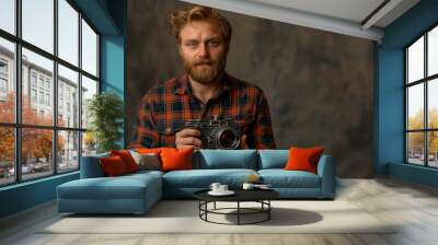 Stylish attractive cameraman in a checkered shirt holds in the hands of an old movie camera Wall mural