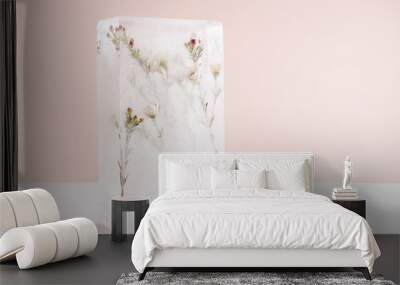 Blooming white sakura flowers frozen with green leaves in transparent ice rectangle block in sun beam on pastel light pink wall, wood table as spring or winter abstract floral background, copy space. Wall mural