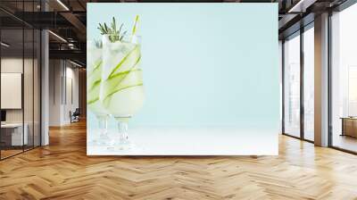 Summer fresh detox cucumber cocktails in wineglasses with ice cubes, rosemary, straw on pastel mint color background, copy space. Wall mural