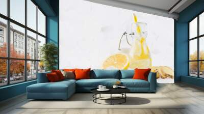 Summer homemade drink - infused lemon water with ice cubes, ginger, slices, soda, straw in yoke bottle in soft light white interior, copy space. Wall mural