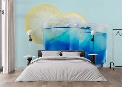 Youth fresh alcohol blue Hawaii cocktail with liquor curacao, ice cube, salt rim, lemon slice on elegant pastel mint background, white wood board. Wall mural