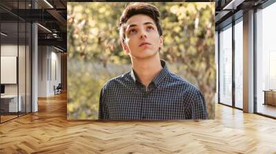 Pensive teenage boy looking up hoping Wall mural