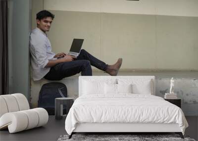 A university student is learning lessons online while sitting at the university campus Wall mural