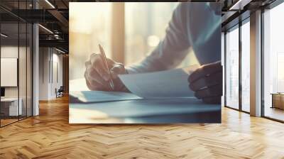 Businessman sitting at desk, holding pen and thoughtfully examining document, symbolizing business buyout and strategic decision-making process. Wall mural