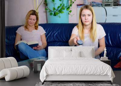 woman reading a book and her daughter watching TV Wall mural