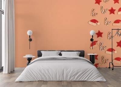 Christmas decorations in shape of stars, santa hats and text ornaments saying 'Merry Christmas' and 'ho ho ho' on side of beige background with copy space Wall mural