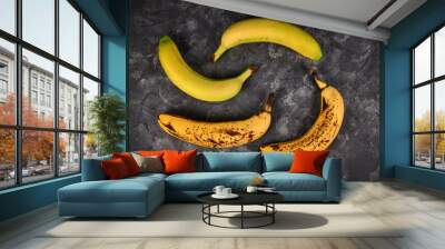 Comparison of ripe bananas with black patches and slightly green bananas on black background Wall mural