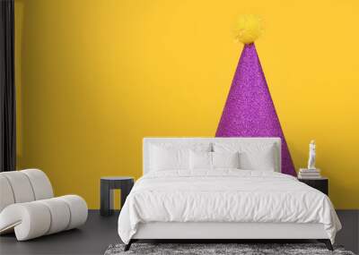 Glittering purple party hat on yellow background with copy space Wall mural