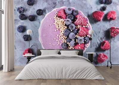 Healthy fruit smoothie bowl with yogurt decorated with raspberry, blueberry and puffed quinoa grain on gray background, top view Wall mural