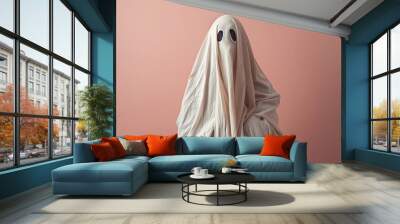 Person in simple Halloween Ghost costume made out of white blanket in front of pink background Wall mural