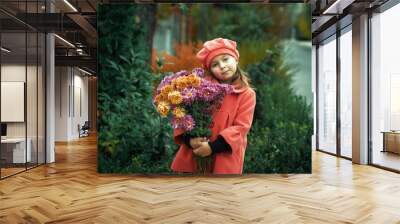 Portrait of a beautiful little girl with chrysanthemums on an autumn walk . Child in a coat and beret Wall mural