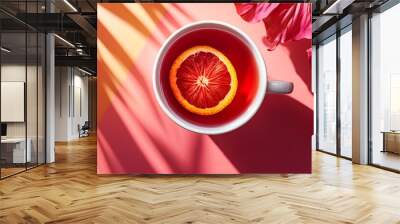 A cup of hibiscus tea, with a slice of orange floating in the warm liquid, set against a vibrant, tropical background Wall mural