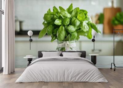 A fresh basil bouquet tied with ribbon, placed in a small glass vase on a kitchen counter Wall mural