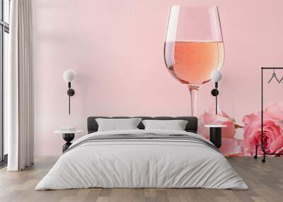 A glass of sparkling rose wine with a few edible rose petals floating on the surface, set against a pastel background Wall mural