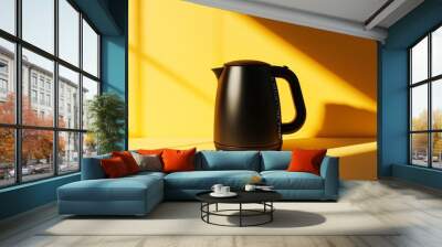 A matte black electric kettle on a pastel yellow surface, minimalist and clean reflections casting soft shadows Wall mural