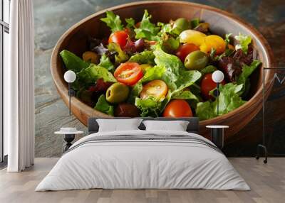 A vibrant summer salad with mixed greens, colorful cherry tomatoes, and green olives, served in a wooden bowl on a rustic table Wall mural