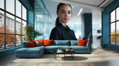 A woman with a serious, confident expression, holding a phone, ready for business in a sleek, modern office setting Wall mural