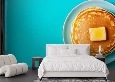 Golden brown pancakes with a pat of melting butter, set on a vibrant turquoise background, creating a colorful breakfast scene Wall mural