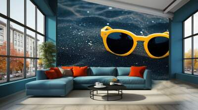 Golden yellow sunglasses on a dark charcoal beach Wall mural